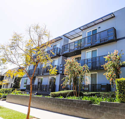 a blue apartment building with a sidewalk and trees in front of it