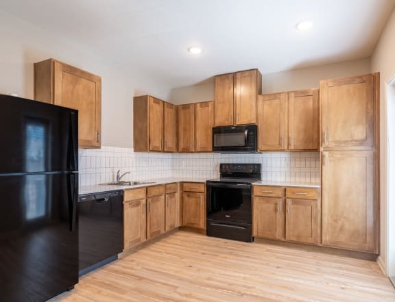 an empty kitchen with wooden cabinets and black appliances