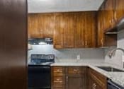 Thumbnail 8 of 28 - Kitchen with dark wood cabinets and stainless appliances at Verano Oaks Apartments