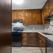 Kitchen with dark wood cabinets and stainless appliances at Verano Oaks Apartments