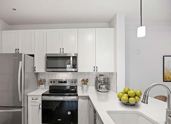 A modern kitchen with a stainless steel refrigerator and a black stove top oven.