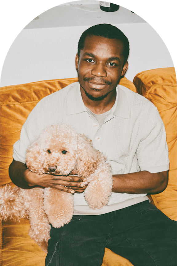 A man is sitting on a couch holding a dog.