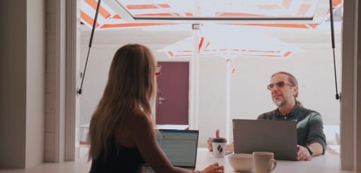 a man and a woman sitting at a table with laptops