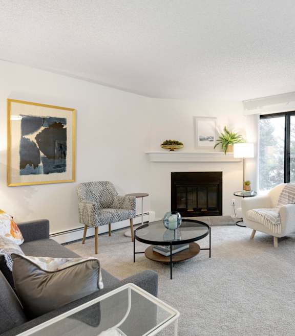 A living room with a grey couch, a fireplace, and a painting on the wall.