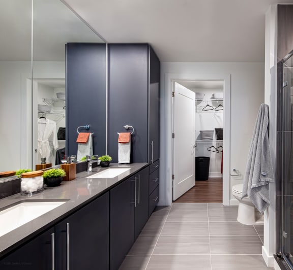 a bathroom with black cabinets and a shower and a counter with two sinks