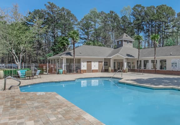 A large swimming pool in front of a building surrounded by trees.