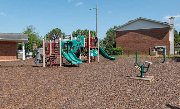 A playground with a green slide and a red and green play structure.