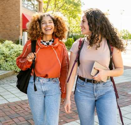 Two women walking together on a sunny day.