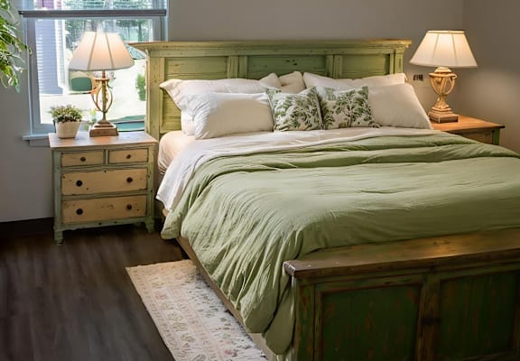 A bedroom with a green bed and a painting on the wall.