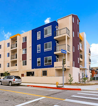 a large apartment building on a street corner with cars parked in front of it