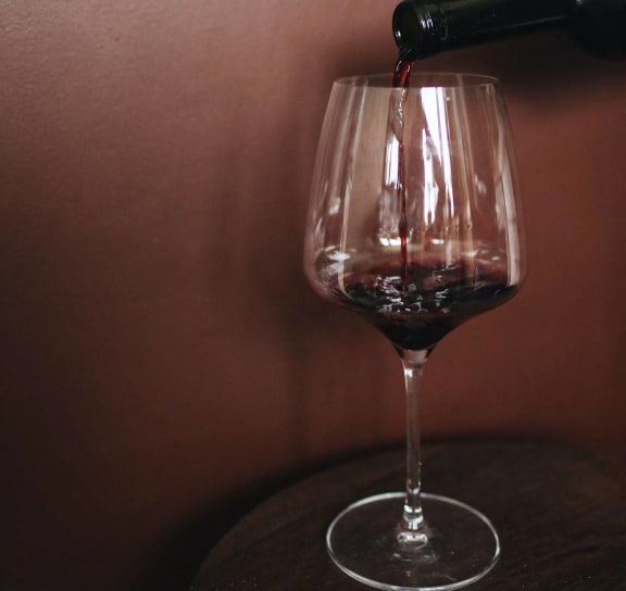 a bottle of red wine pouring into a wine glass