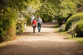 A family of three walks down a dirt road in a park.