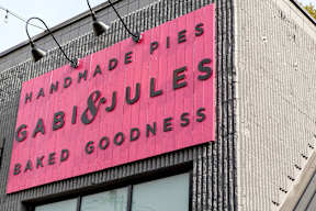 A pink sign on a building advertises Gabi's Handmade Pies and Gabi's Baked Goodness.