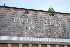 A sign that says Twin Sails Brewing is on a building.