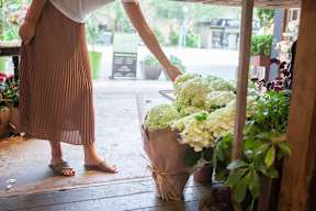 A woman in a brown skirt is holding a bouquet of flowers.