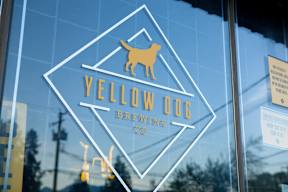 A glass window with a logo of a dog and the text Yellow Dog Brewing Co.