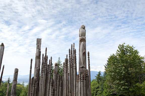 a group of wooden totem poles against a cloudy sky
