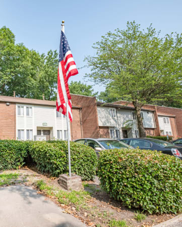 a flagpole with an american flag in front of a brick apartment building