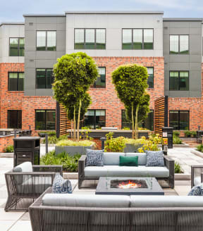 an outdoor lounge area with couches and a fire pit in front of a building at The Ivy, Chatham, NJ 07928