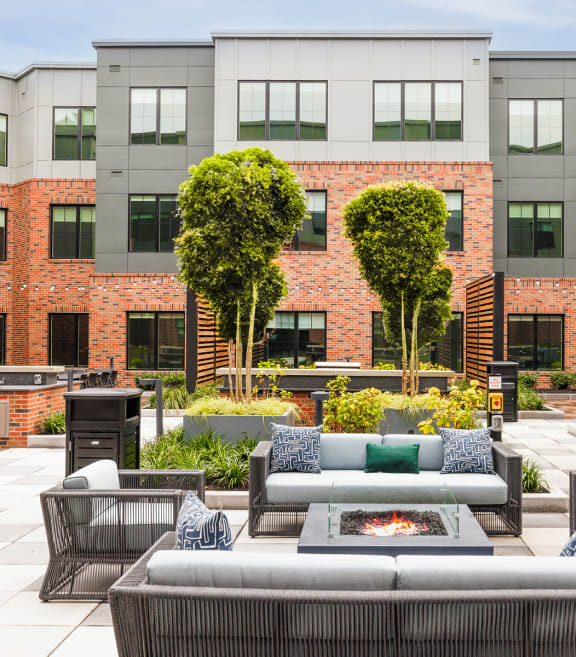 an outdoor lounge area with couches and a fire pit in front of a building at The Ivy, Chatham, NJ 07928