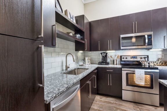 Westwood Green Apartments Kitchen with stainless appliances, grey quarts countertops, and white subway tile backsplash