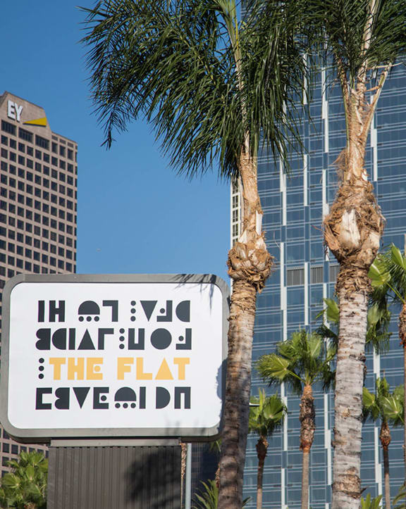 a sign for the flat heaven in front of palm trees at The Flat in Los Angeles, California 90017