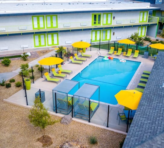 A pool surrounded by yellow umbrellas and a fence.