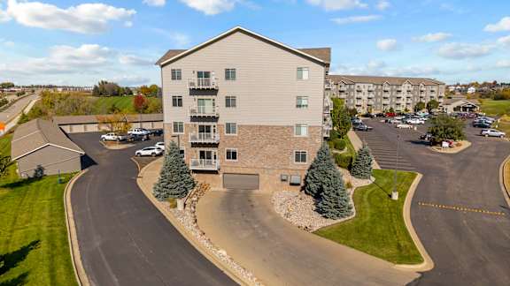 A large apartment complex with a parking lot in front.
