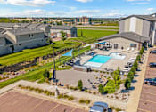 Thumbnail 1 of 8 - A large building complex with a pool and parking lot.