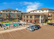 Thumbnail 9 of 10 - A sunny day at a parking lot with cars and apartment buildings.