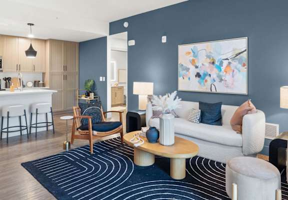 A modern living room with a kitchen area in the background. at Lucie at Tradition Apartments, Port St. Lucie, FL