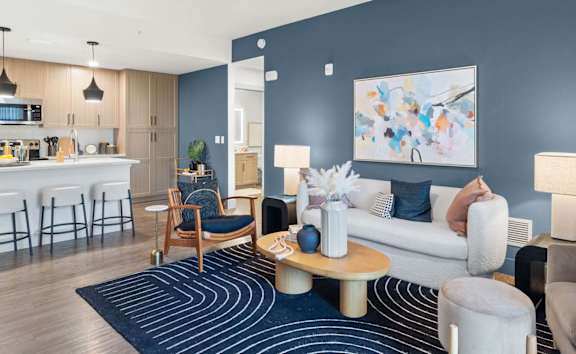 A modern living room with a kitchen area in the background. at Lucie at Tradition Apartments, Port St. Lucie, FL, 34987
