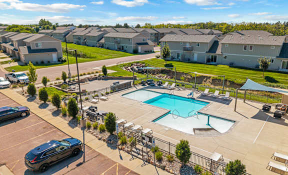 A swimming pool surrounded by a fence and a parking lot.