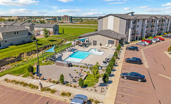 A large building complex with a pool and parking lot.