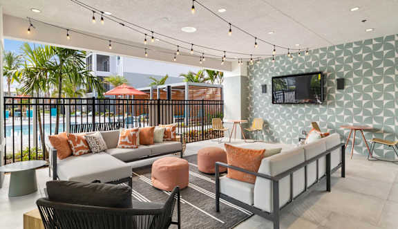 A modern outdoor seating area with a pool in the background. at Lucie at Tradition Apartments, Port St. Lucie, FL, 34987