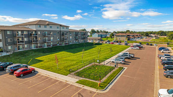 A parking lot with cars and a grassy area in front of a building.