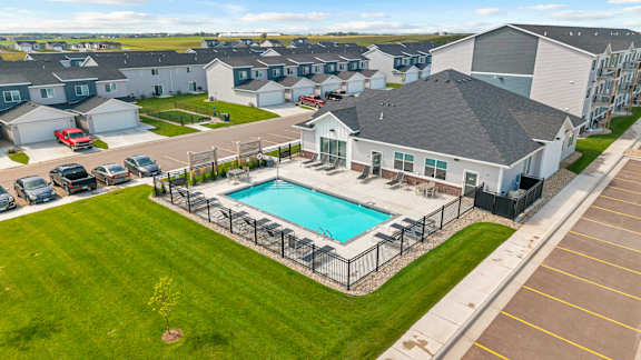 A swimming pool is surrounded by a fence in a grassy area.
