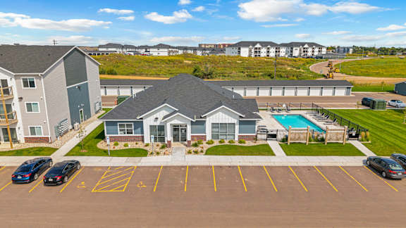 A parking lot with a building and a pool in the background.