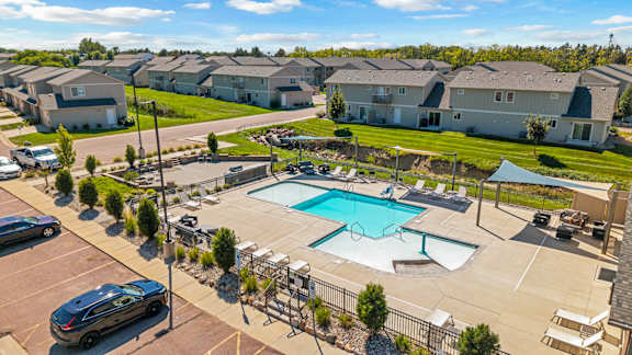 A swimming pool surrounded by a fence and a parking lot.