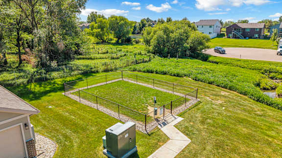 A green field with a fence and a small building in the middle.