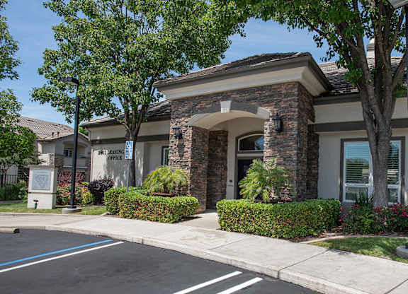 A clubhouse with a stone archway entrance and a sign at Stoneridge Apartments, California, 95661