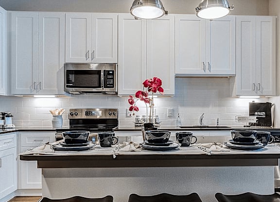 A kitchen with white cabinets and a grey island.