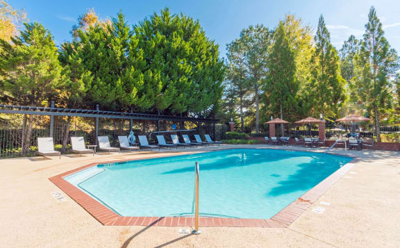 a swimming pool with chairs around it and trees in the backgroundat Mill Creek Place, Douglasville Georgia