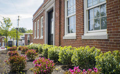 A red brick building with a flower bed in front.