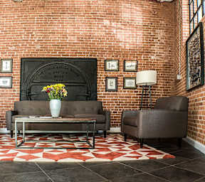 Lobby seating area with exposed brick wall at Star Mill Lofts Apartments, Middleboro, MA 02370