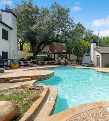 Community Swimming Pool with Pool Furniture at Heatherstone Apartments in Dallas, TX-HERO.