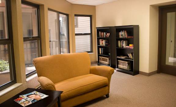 a living room with a yellow chair and a book shelf