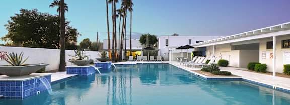A swimming pool surrounded by palm trees and lounge chairs.at Winfield of Scottsdale, Scottsdale, AZ 85251