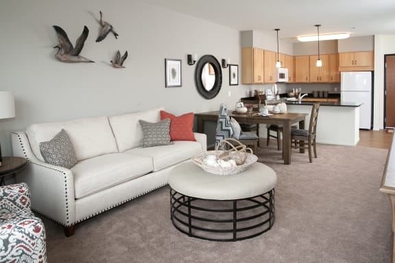 a living room with a couch and a table in front of a kitchen at The Grainwood Senior Apartments, Minnesota