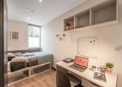 Thumbnail 1 of 16 - a bedroom with a bed and a desk with a laptop